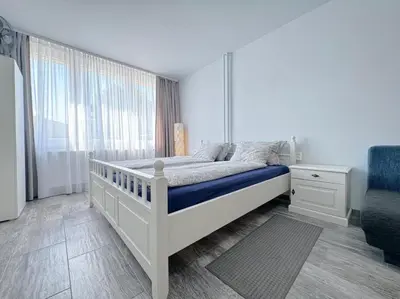 a white bedroom with a bed and a window at Apartment Střížkov in Prague