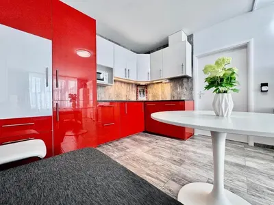 a red kitchen with a white table and red cabinets at Apartment Střížkov in Prague