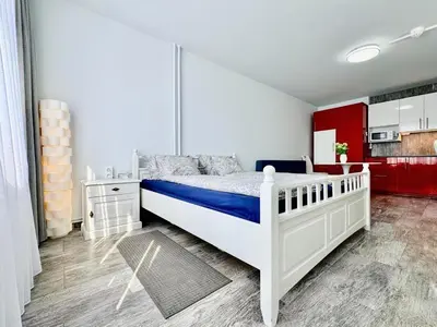 a bedroom with a white bed and a red kitchen at Apartment Střížkov in Prague