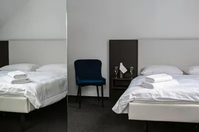 a bedroom with two beds and a blue chair at Golden Golem hotel & Spa in Prague