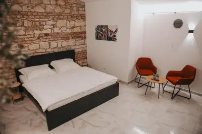 a bedroom with a bed and two red chairs at Zizkoff apartments in Prague