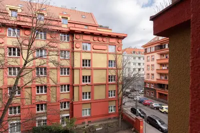 a tall red building with cars parked in front of it at Gallery Apartment in Prague