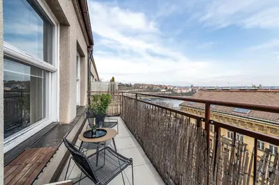 a balcony with a table and chairs and a view at Top Floor Industrial Apartment with a River View in Prague