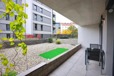 a small garden with a green lawn in a building at Modern Apartment • Garden • Near The City Center in Prague