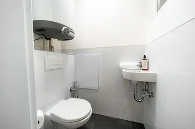 a white bathroom with a toilet and a sink at Secret Budget Studio Oasis in Prague