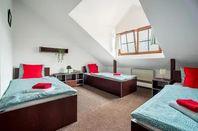 a attic bedroom with two beds and a window at Ubytování Ostende - penzion in Chocerady