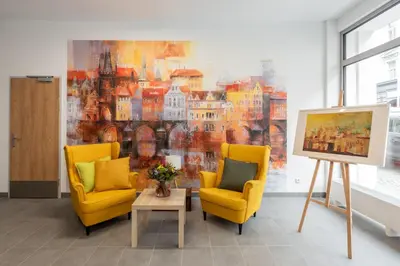 a living room with two chairs and a painting at Libero Apartments in Prague