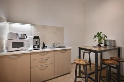 a kitchen with a sink and a table with stools at Boutique Residence by Little King in Prague