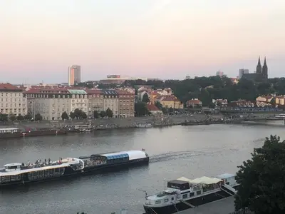 a boat on a river with a city in the background at Spectacular Prague Views room for 1 or 2 in Prague