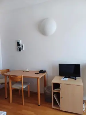a room with a table and a desk with a television at Centrum Mariapoli in Prague