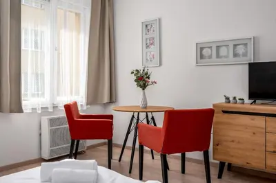 a living room with two chairs and a table and a television at Art Deco Suite in Prague