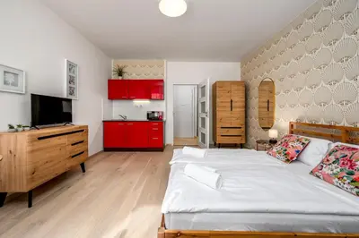 a bedroom with a bed and a kitchen with red cabinets at Art Deco Suite in Prague
