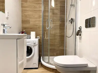 a bathroom with a shower toilet and a washing machine at Parkside Studio in Vinohrady in Prague