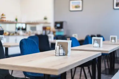 a row of tables in a restaurant with blue chairs at Hotel Leon in Prague