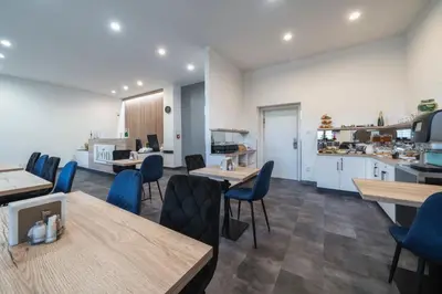 a room with tables and chairs and a kitchen at Hotel Leon in Prague