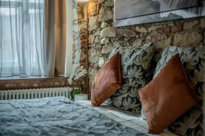 a bedroom with a bed with pillows and a stone wall at Centre Prague Retreat Residence in Prague