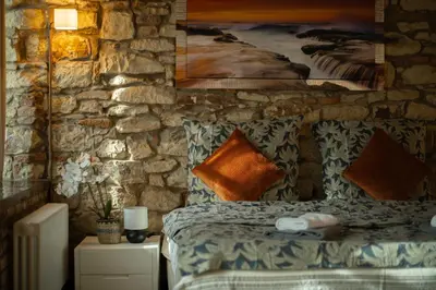 a bedroom with a stone wall with a bed and a painting at Centre Prague Retreat Residence in Prague