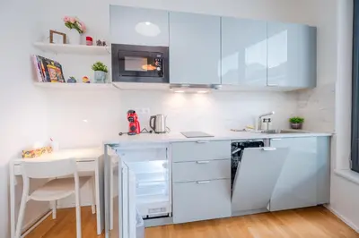 a kitchen with white cabinets and a table at New-built Golden Luxury Studio with Balcony in Prague