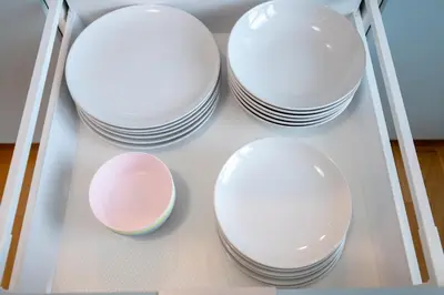 four white plates and bowls sitting on a shelf at New-built Golden Luxury Studio with Balcony in Prague