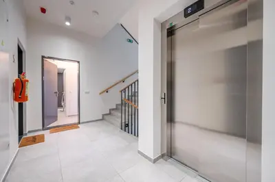 a hallway with white walls and a metal elevator at New-built Golden Luxury Studio with Balcony in Prague