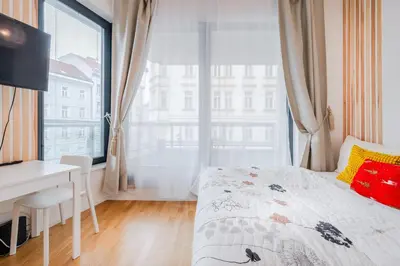 a bedroom with a bed and a desk and a window at New-built Golden Luxury Studio with Balcony in Prague
