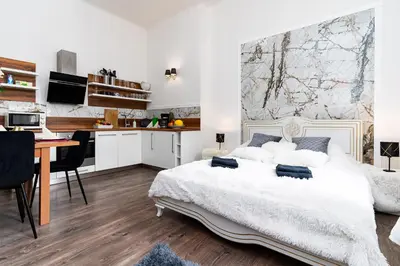 a bedroom with a bed and a desk and a kitchen at Grand Deluxe Suite in Prague