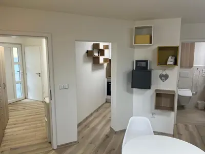a white room with a white table and a kitchen at Relax pobyt na břehu Sázavy a na dosah Prahy in Čerčany