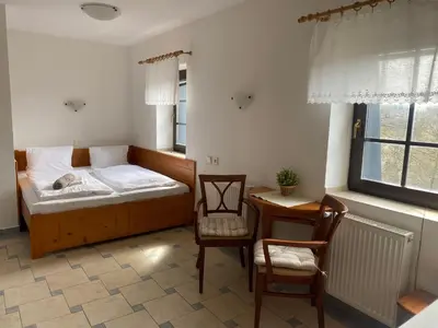 a bedroom with a bed and a table and chairs at Penzion Janata in Slapy