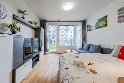 a living room with a bed and a tv at Garden Studio near Metro Kolbenova in Prague