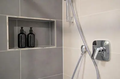 two bottles of wine are sitting on a shelf in a shower at Colorful Apartment - Balcony, Free Parking, by Gravity Prague in Prague