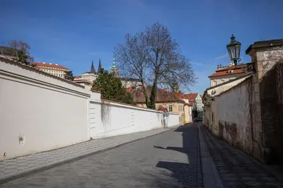 an empty alley with a white wall and a street at Grace Apartment by Prague Castle in Prague
