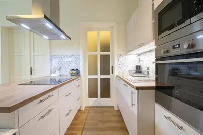 a kitchen with white cabinets and black appliances at Stay Inn Apartments Ve smeckah in Prague