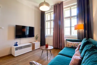 a living room with a blue couch and a tv at Stay Inn Apartments Ve smeckah in Prague