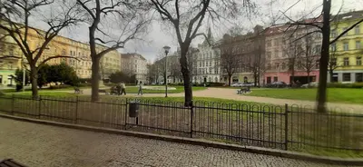 a fence in front of a park with buildings at Small Sunny park view apartment in Prague