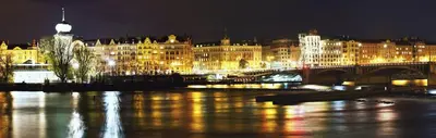 a city at night with a bridge and buildings at Small Sunny park view apartment in Prague