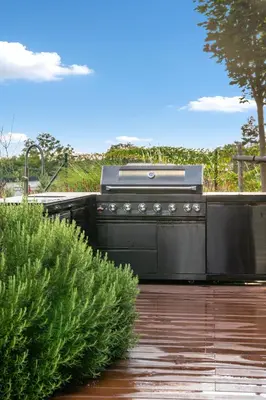 a grill on the back of a patio with some bushes at Chandelier Sky Mansion in Tuchoměřice