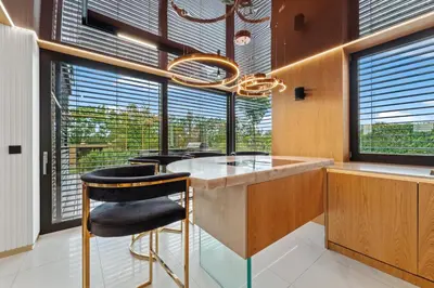 a kitchen with a counter with a chair and windows at Chandelier Sky Mansion in Tuchoměřice
