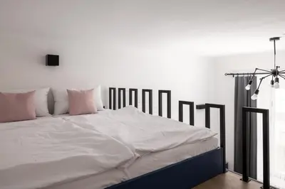 a large bed with white sheets and pink pillows at Stay2gether M&M Studio Holešovice in Prague