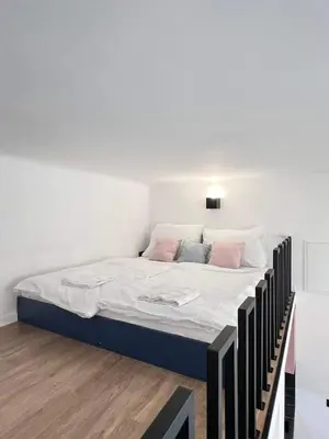 a bed with white sheets and pink pillows in a room at Stay2gether M&M Studio Holešovice in Prague