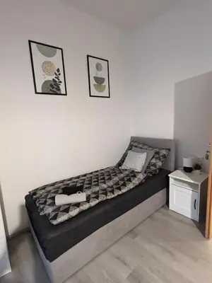a bed in a bedroom with two pictures on the wall at Penzion Grand Nymburk in Nymburk
