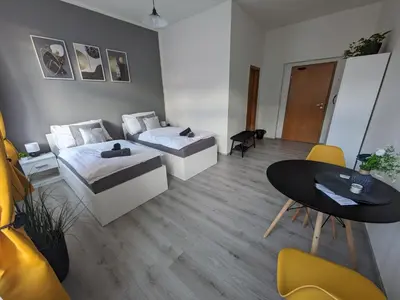 a room with two beds and a table and chairs at Penzion Grand Nymburk in Nymburk