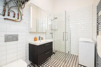a white bathroom with a sink and a shower at Prague Days - Spacious Apartment with Balcony near Wenceslas Square in Prague