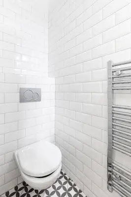 a white bathroom with a toilet and a tiled wall at Prague Days - Spacious Apartment with Balcony near Wenceslas Square in Prague