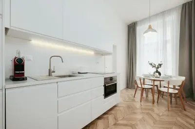 a kitchen with white cabinets and a table with chairs at Prague Days - Spacious Apartment with Balcony near Wenceslas Square in Prague