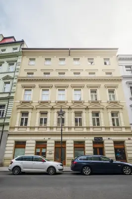 two cars parked in front of a large building at Prague Days - Deluxe Two-bedroom Apartment in New Town in Prague