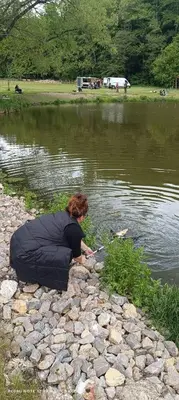 a woman sitting on the rocks near the water at Apartmán Ve Mlýně in Třebotov