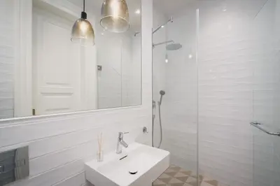 a white bathroom with a sink and a shower at Palace Dlazdena – Stylish Prague Centre Apartment in Prague