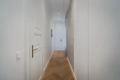 a hallway with white doors and a wooden floor at Palace Dlazdena – Stylish Prague Centre Apartment in Prague