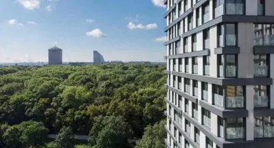 a tall building in front of a forest of trees at Residence Garden Tower - Parking in Prague
