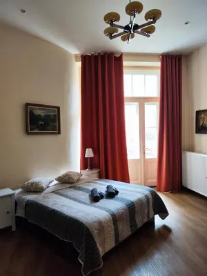 a bedroom with a large bed with red curtains at Stella apartments in Prague